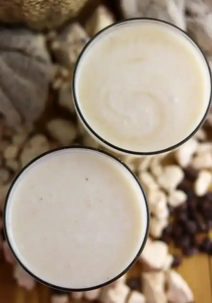 Two glasses of baobab juice with fresh baobab fruit in the background, a refreshing drink made with baobab powder.