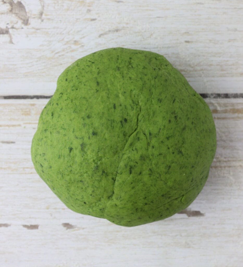 image showing how green wild garlic pasta dough ball looks like when kneaded enough, before chilling it in the refrigerator