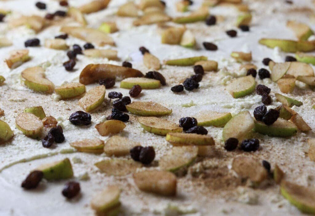 Raisins being tossed over the pear strudel phyllo dough before rolling. 