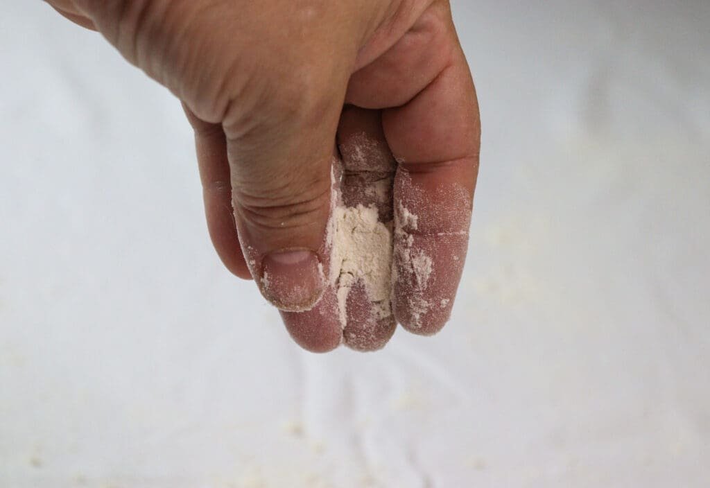 How to sprinkle the covered kitchen table with flour before stretching the strudel dough.