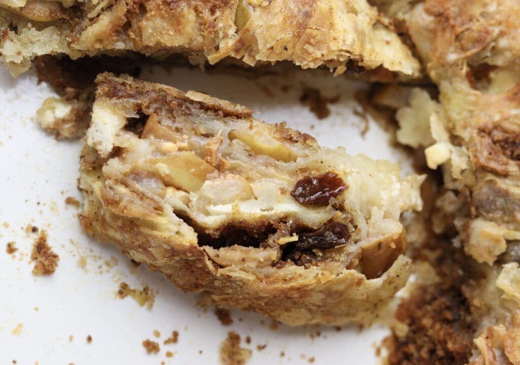 A piece of delicious homemade pear cheese strudel with raisins and toasted breadcrumbs in a baking tray. 
