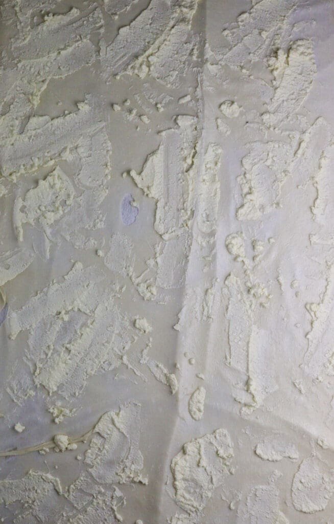 Adding cottage cheese mixture to the freshly made, stretched strudel phyllo sheet. 