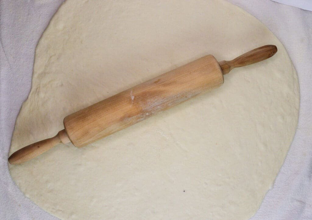 Rolling out the strudel phyllo pastry dough on a white sheet, sprinkled with flour. 