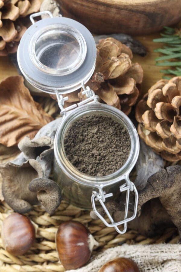 a top view of an open jar full of black trumpet (craterellus cornucopioides) powder