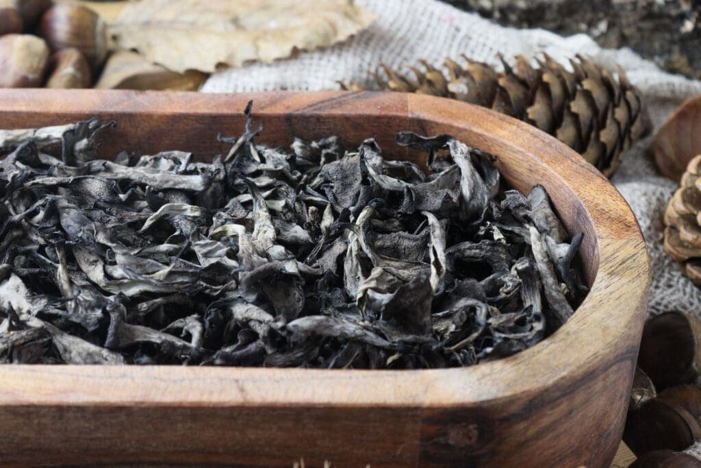 Dried black trumpets in a wooden bowl waiting to be transformed into magical mushroom powder