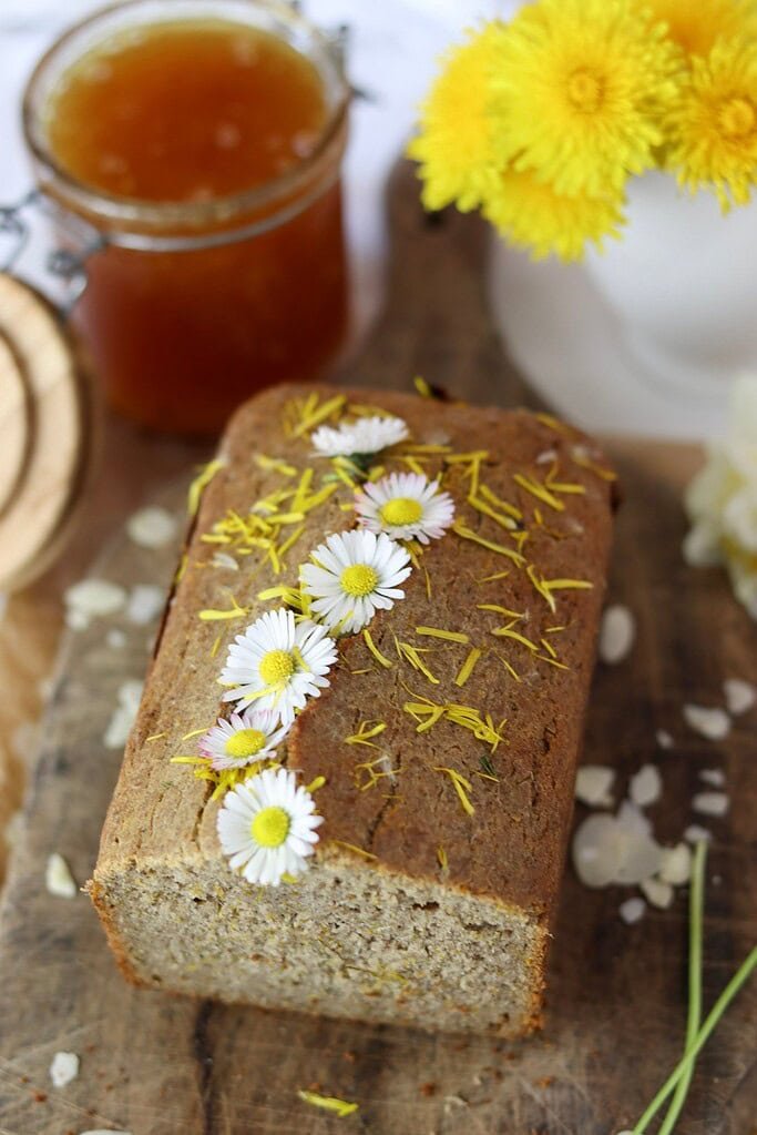 Gluten-free dandelion buchweat bread with honey and daisies on top of the loaf. 