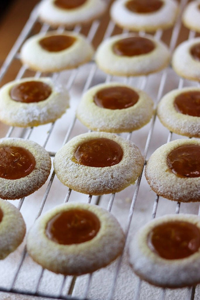 Beautiful dandelion thumbprint cookies, just sprinkled with powdered sugar, cooling on a rack