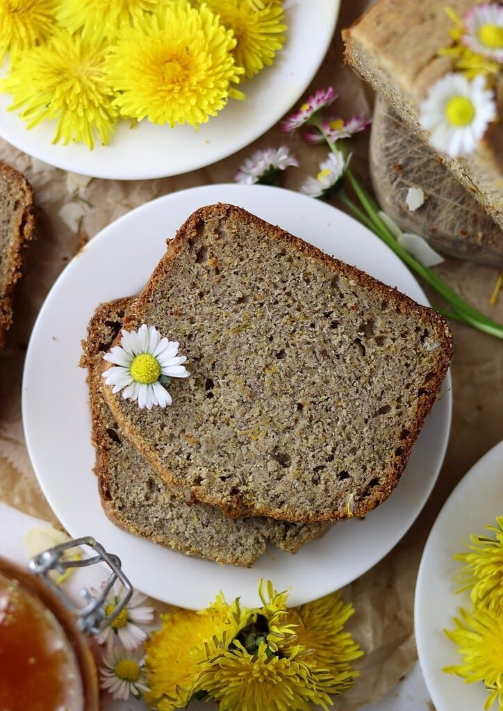 A piece of buckwheat dandelion bread with dandelion flowers in the background. 