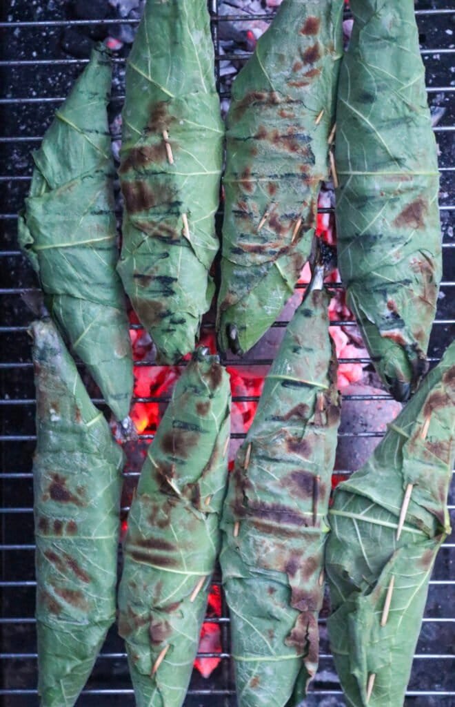 Fig leaf wrapped fish on a charcoal grill just before  ready to be eaten.