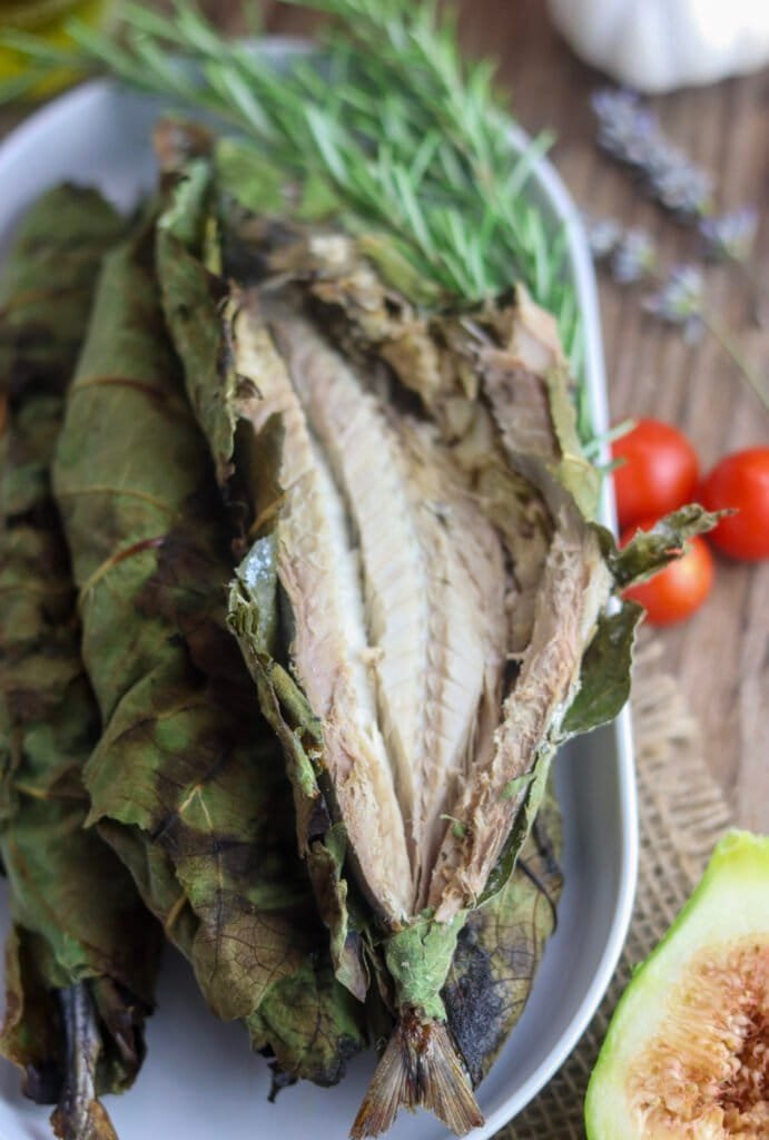 A full plate of fig leaf grilled wish with rosemary, the one on the top showing a delicious inside.