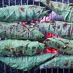 Fig leaf wrapped fish on a charcoal grill just before ready to be eaten.