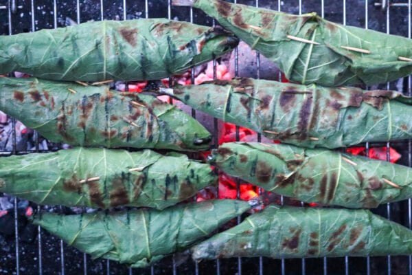Fig leaf wrapped fish on a charcoal grill just before ready to be eaten.