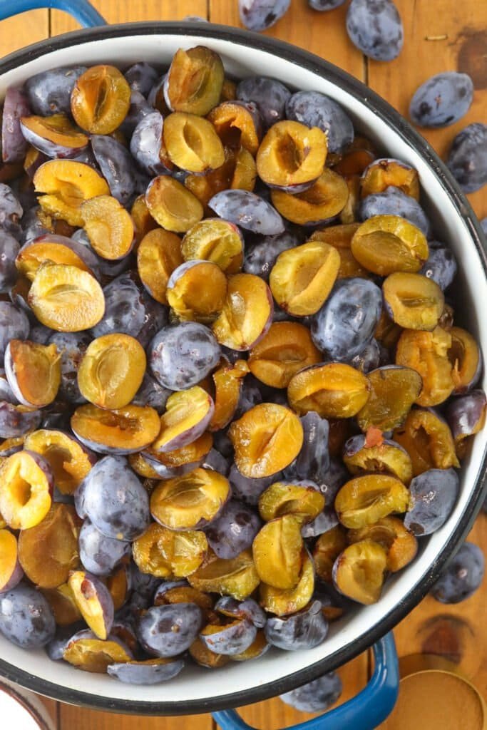 Pited and halved plums in a large cooking pot prepared for the keto plum jam.