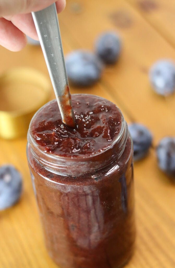 Pressing down the jam in the jar to avoid large air bubbles.