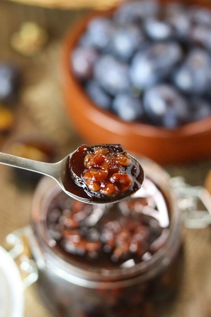 A teaspon with a bite of plum baked in honey with a walnut.