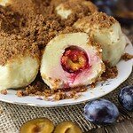Plum dumplings with spelt flour and cottage cheese dessert with fresh plums in the background.