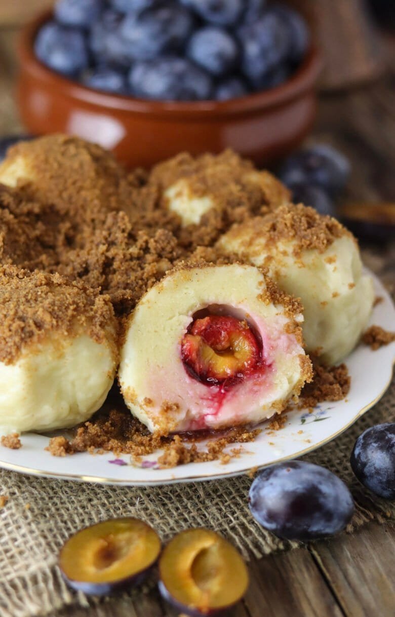 Plum dumplings with spelt flour and cottage cheese dessert with fresh plums in the background.