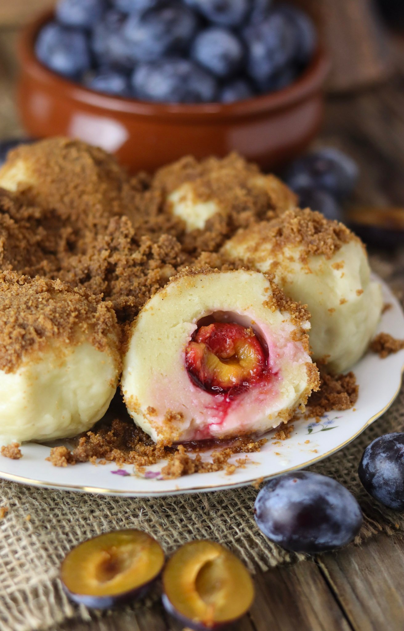Plum dumplings with spelt flour and cottage cheese dessert with fresh plums in the background.