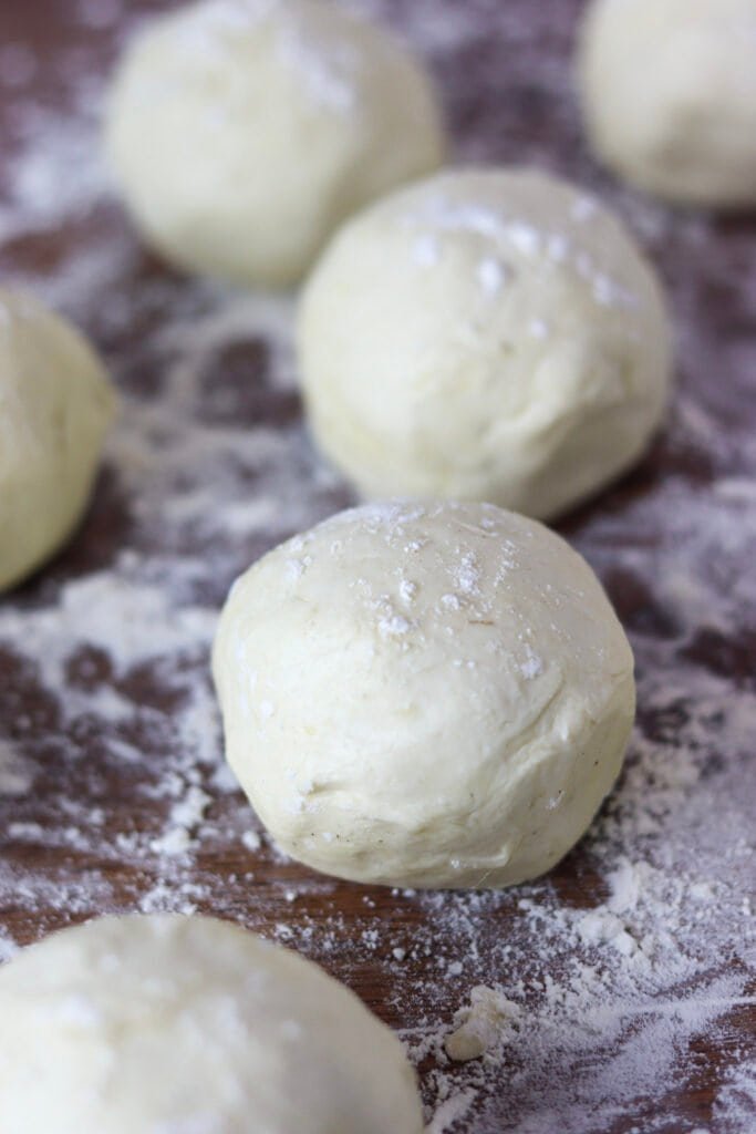 Balls of plum dumplings on a wooden kitchen counter, ready to be cooked.