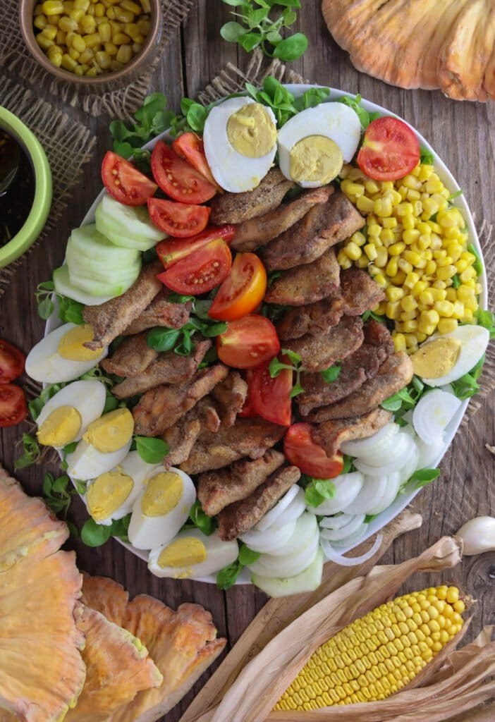 Top view of fried chicken of the woods mushroom salad plate with corn, lettuce and fresh mushrooms in the background.