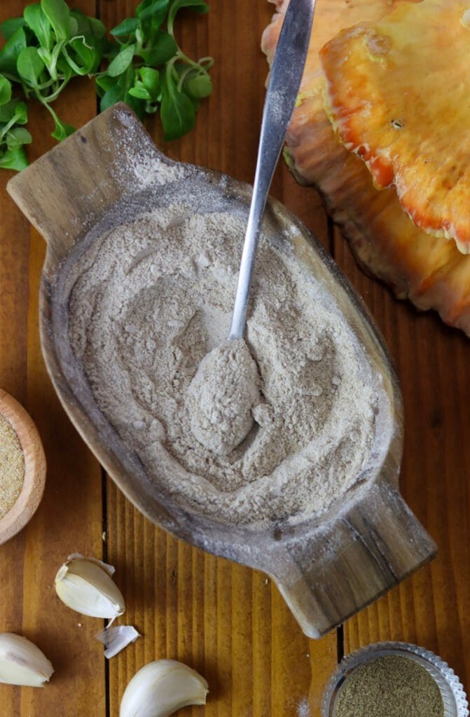Buckwheat flour with salt, white pepper and garlic powder in a small wooden bowl.