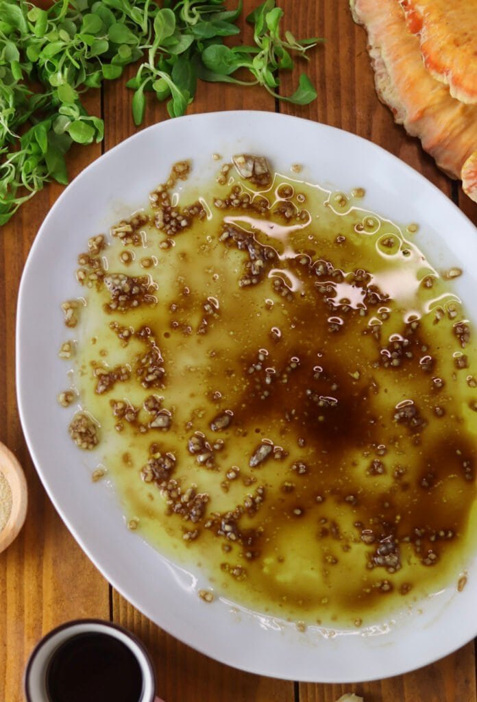 A plate covered with salad dressing with olive oil, vinegar and garlic.