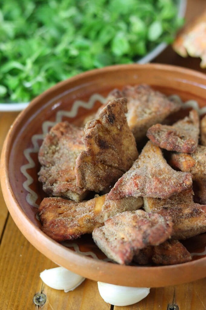 A rustic bowl with fried chicken of the woods slices with lamb's lettuce sallad in the background.