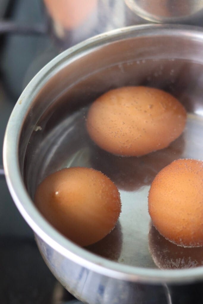 Three ggs in a small pot with boiling water.