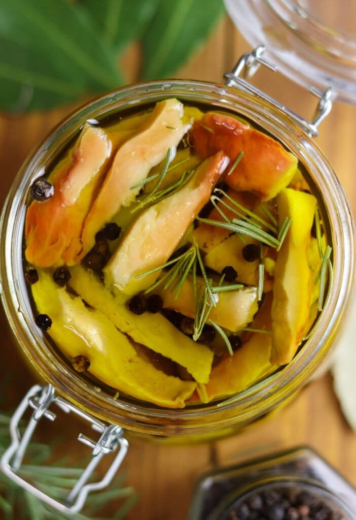 A jar of pickled chicken of the woods mushrooms in olive oil with black pepper, rosemary and bay leaf.