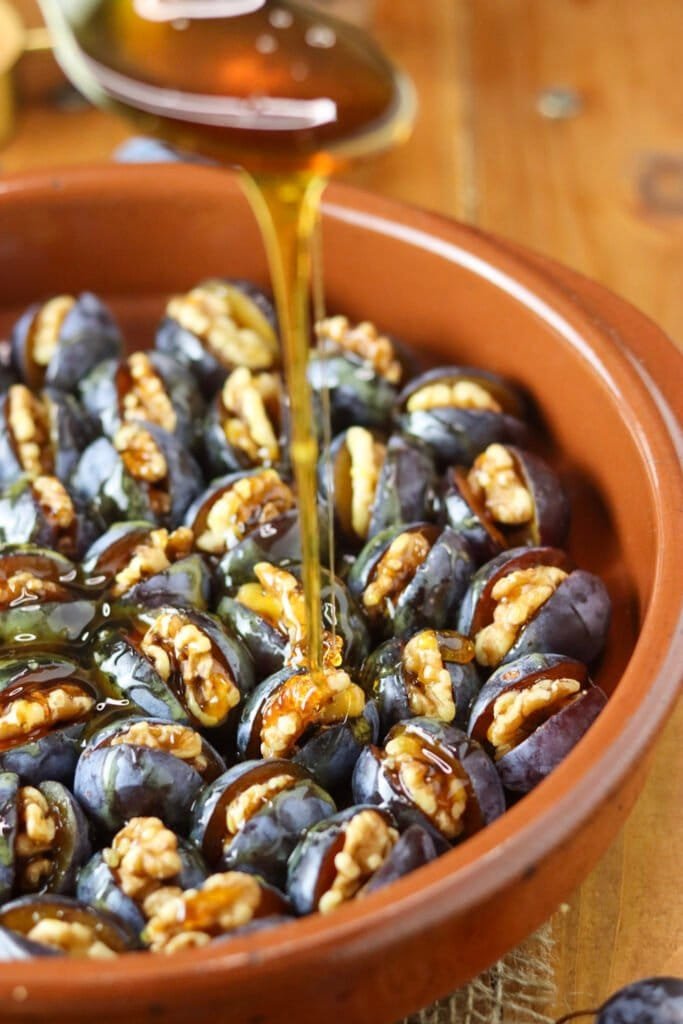 How to pour the honey over filled plums to bake them for a honey plum preserve.