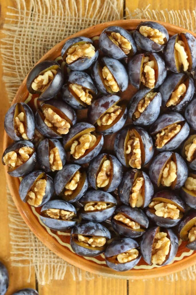 Plums with walnuts on a rustic plate.