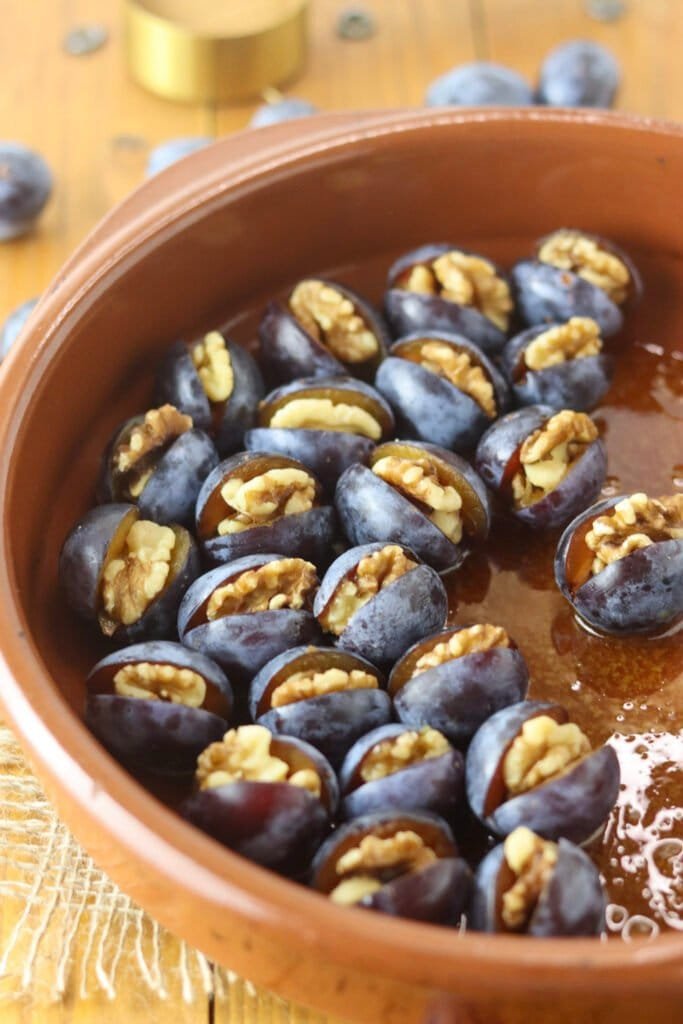 How to place the stuffed plums on a layer of honey in a baking pan.