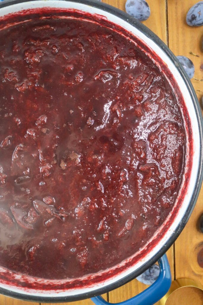 Cooking plums on the stove, slowly reducing them into a thick, sugar free jam.