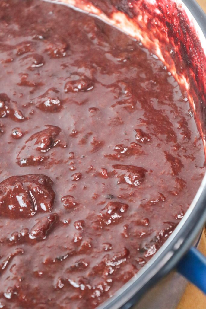 Plum jam in a cooking pot that just started thickening.