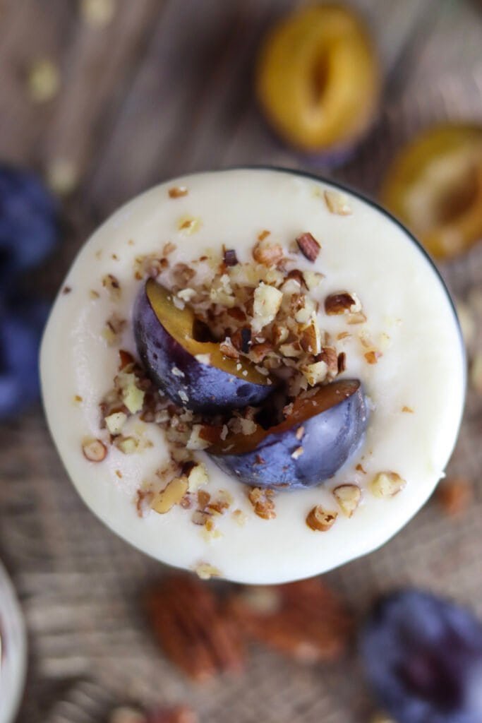 Top view of plum parfait, decorated with plum halves and ground nuts.