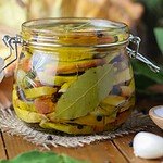A jar of pickled chicken of the woods mushroom with olive oil in a jar, with chicken of the woods mushroom in the background.