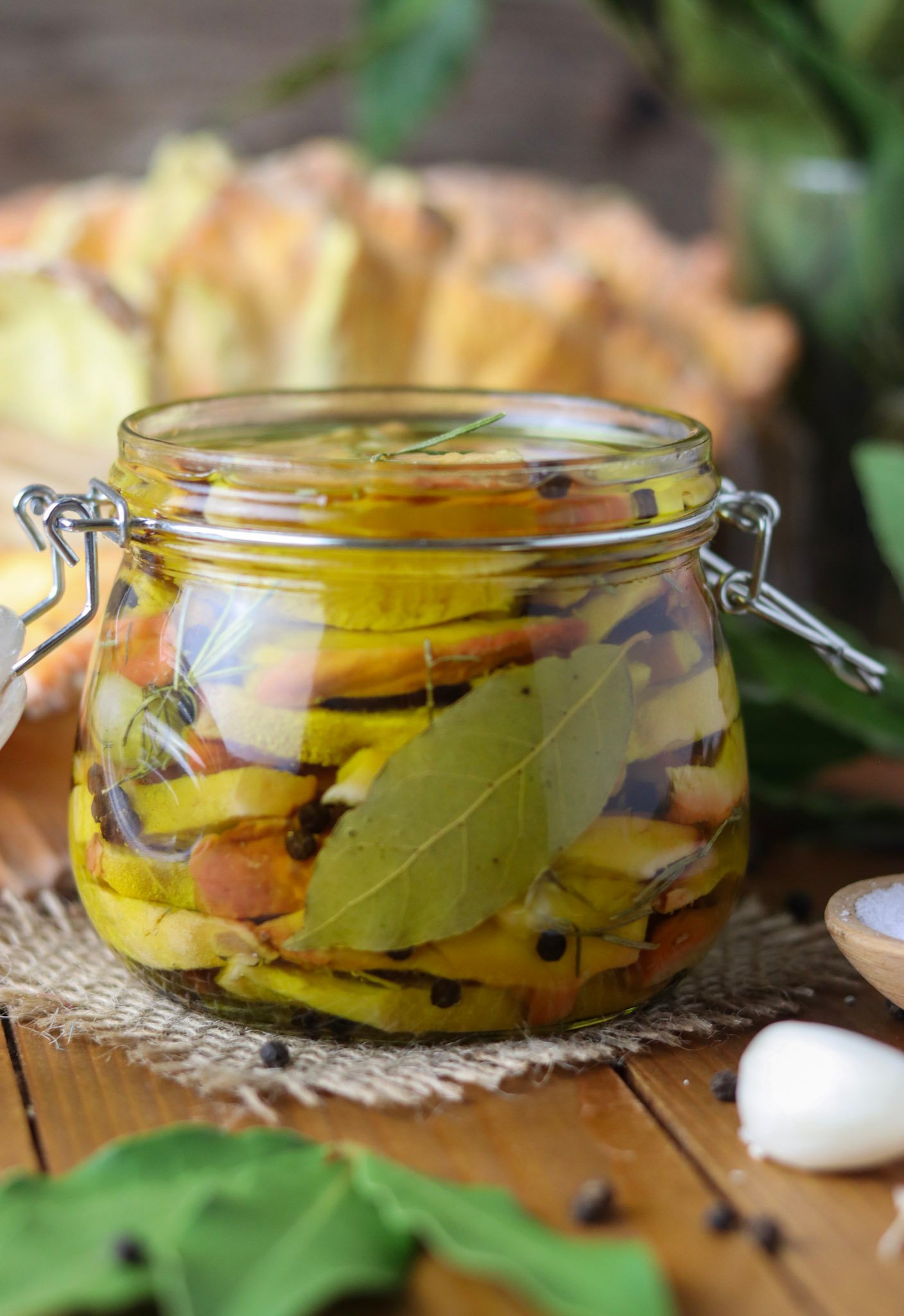 A jar of pickled chicken of the woods mushroom with olive oil in a jar, with chicken of the woods mushroom in the background.
