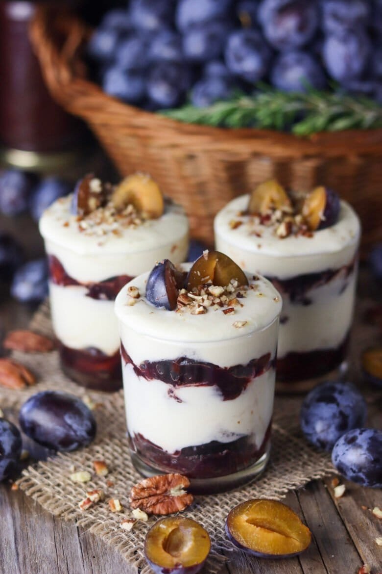 Roasted plum parfait with white chocolate on a wooden rustic table.