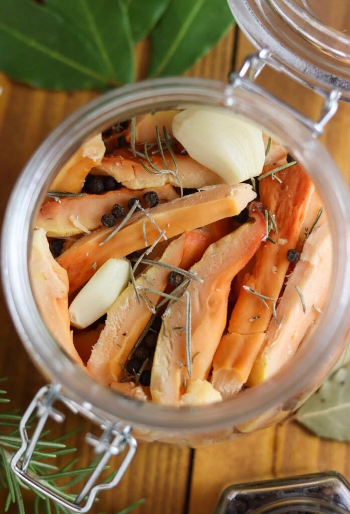 Mushroom slices in a jar with spices, before adding the olive oil.