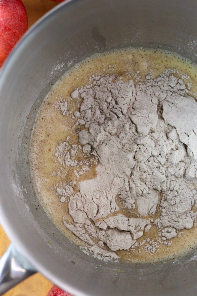 A large bowl with egg, cinnamon, milk and honey mixture and added buckwheat flour on top.