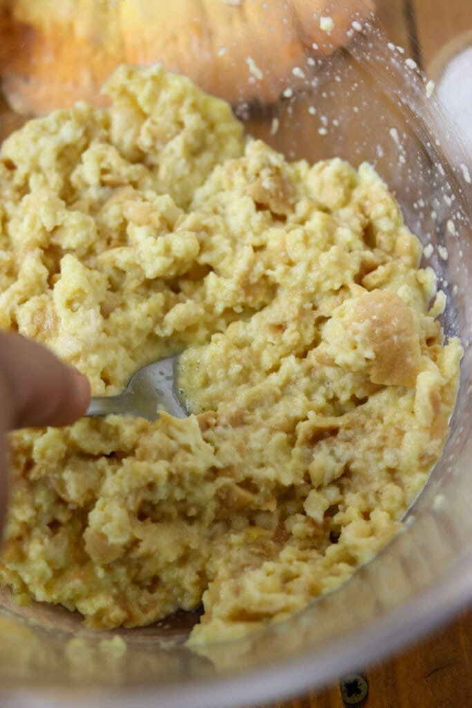 Mashing the bread with eggs in a large glass bowl.