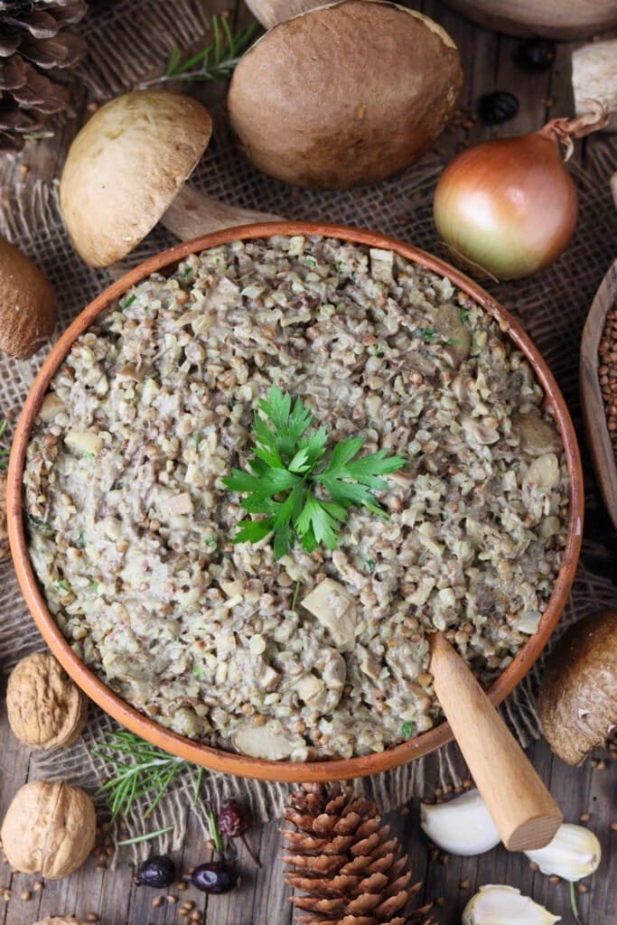 Buckwheat with porcini mushrooms with an onion, pine cones and beautiful fresh porcini in the background.