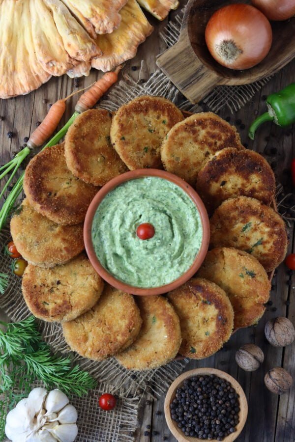 Chicken of the woods mushroom fritters with a green dip on a rustic plate.