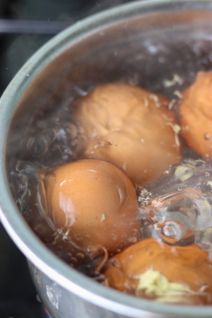Four eggs boiling in a small pot.