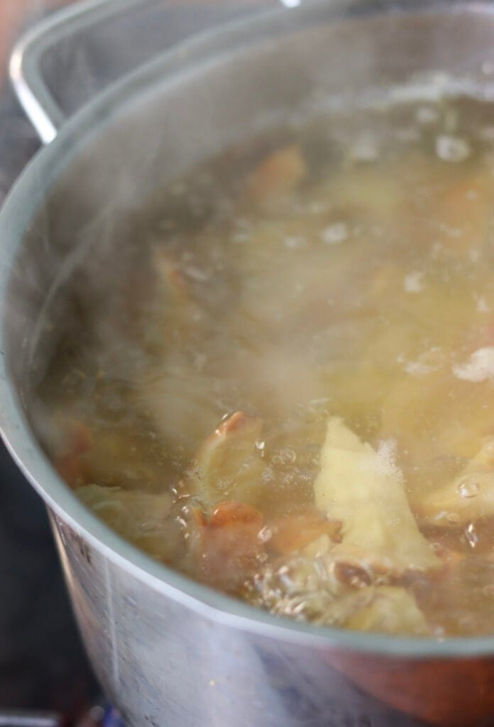 Chicken of the woods slices boiling in a pot of water on a gas burner.
