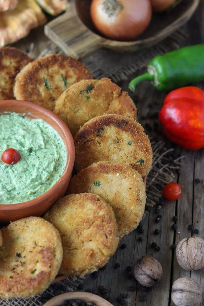 A delicious serving of freshly fried chicken of the woods mushroom fritters with a green dip.
