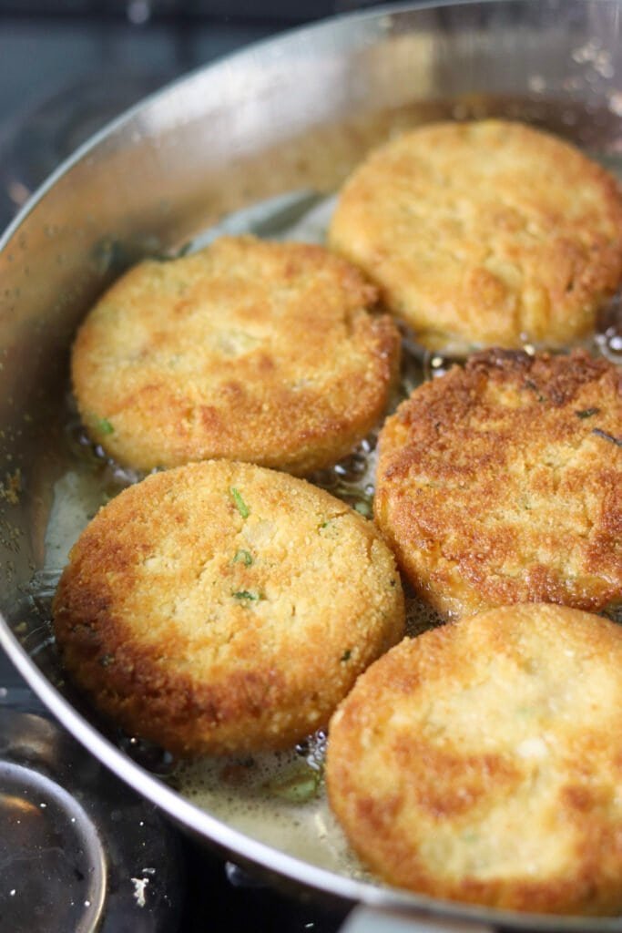 Frying the fritters in hot olive oil in a large pan.