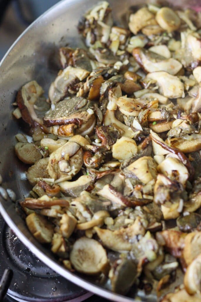 Fired porcini mushrooms with garlic in a frying pan.