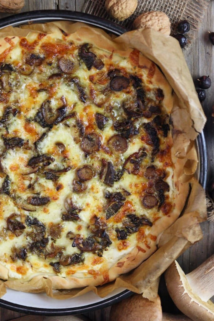 A large round pan with pizza with porcini mushrooms, baked golden brown with browned, melted cheese and porcini on top.