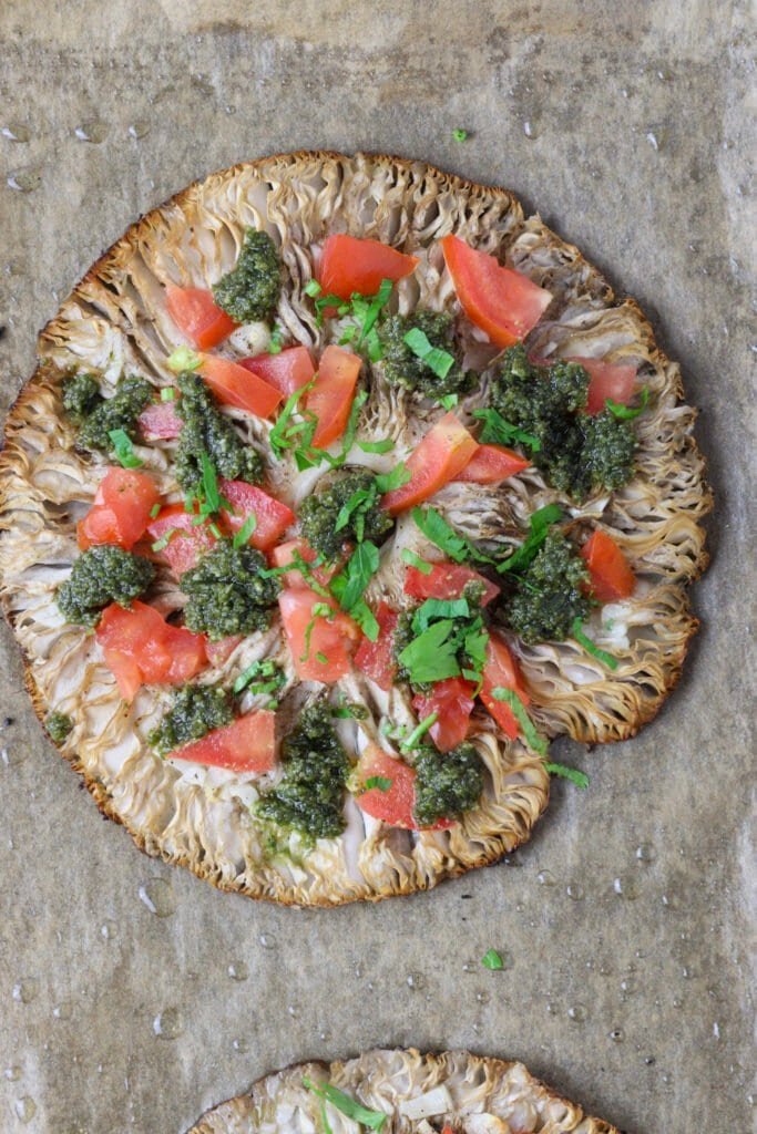Parasol mushroom just being topped with pesto, tomato and fresh parsley.